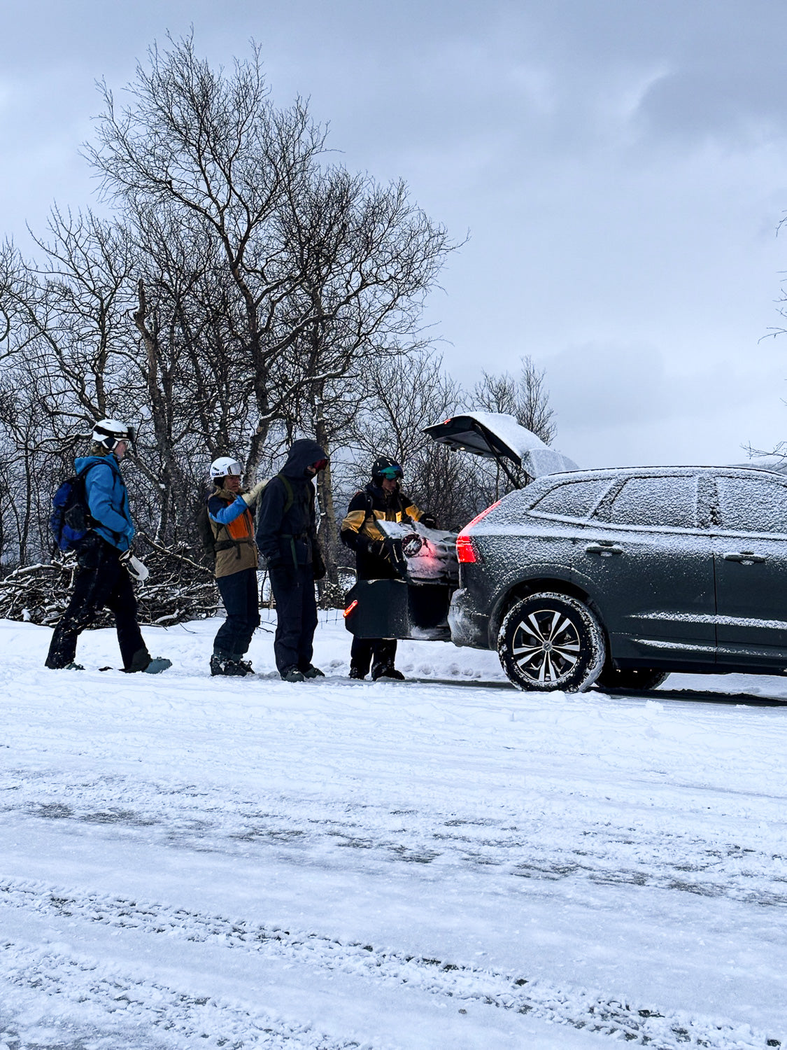 Auto s boxem IXTAbox na tažném zařízení v zimní krajině s lyžaři